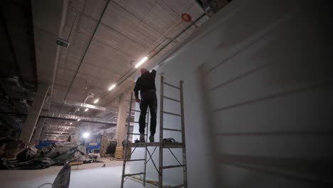 the painter is painting a wall at a large factory.