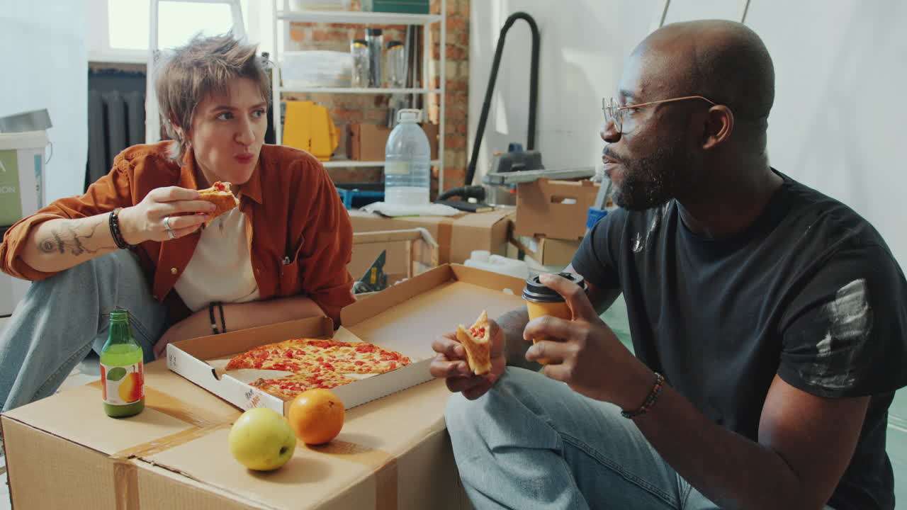 Couple Talking and Eating Pizza on Lunch Break during Home Renovation