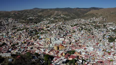 toma aérea rotatoria de drones de la iglesia parroquial de santa prisca en el centro de la ciudad de taxco de alarcón en el estado de guerrero, méxico, rodeada por una cordillera durante el día