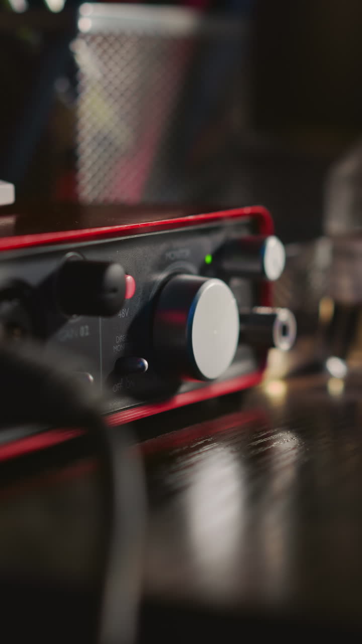 남자가 스튜디오 클로즈업에서 사운드 증폭기를 켜고 음악가가 녹음 스튜디오에서 연주하기 위해 디지털 장비를 준비합니다.