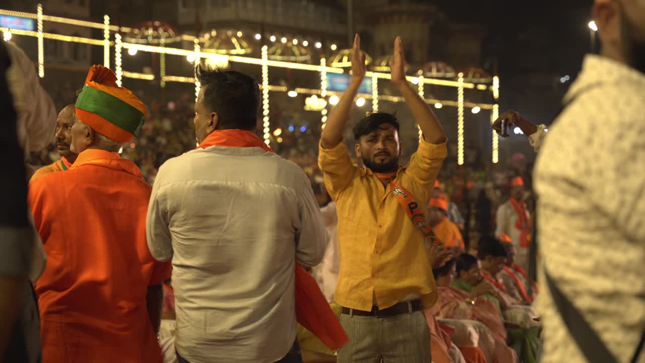 Happy and energetic young Indian men clapping in support for Chief Minister Yogi Adityanath Lok Sabha election campaign rally