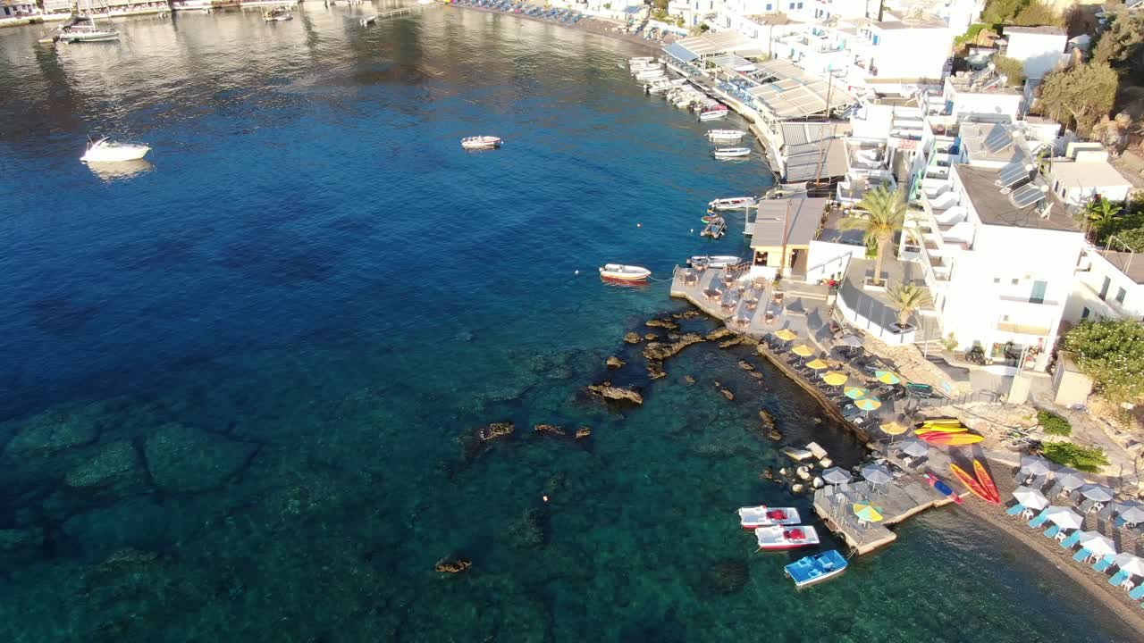 vista de drones en grecia volando sobre el mar azul en loutro pequeña ciudad de casas blancas y pequeños barcos al lado de una colina en un día soleado