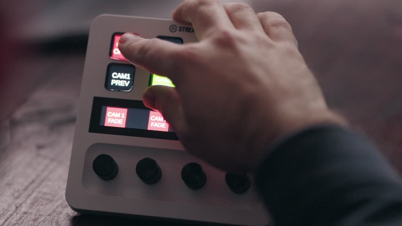 hand pressing buttons on a live streaming switcher, adjusting camera feeds during a broadcast