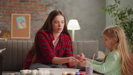 hermana adolescente enseña a la niña a gotear pintura para la decoración de mármol