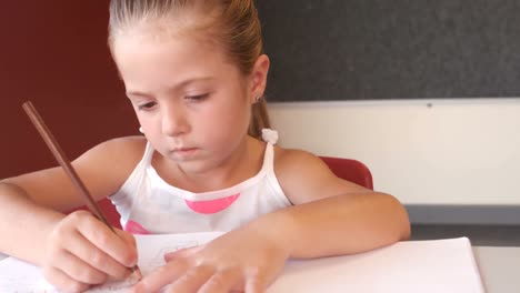 una colegiala linda haciendo la tarea en el aula.