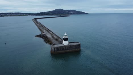 Holyhead-breakwater-lighthouse-longest-concrete-coastal-sea-protection-landmark-aerial-view-slow-lowering-push-in