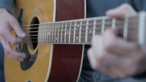 hombre tocando una guitarra afuera, un primerísimo plano y poca profundidad de campo