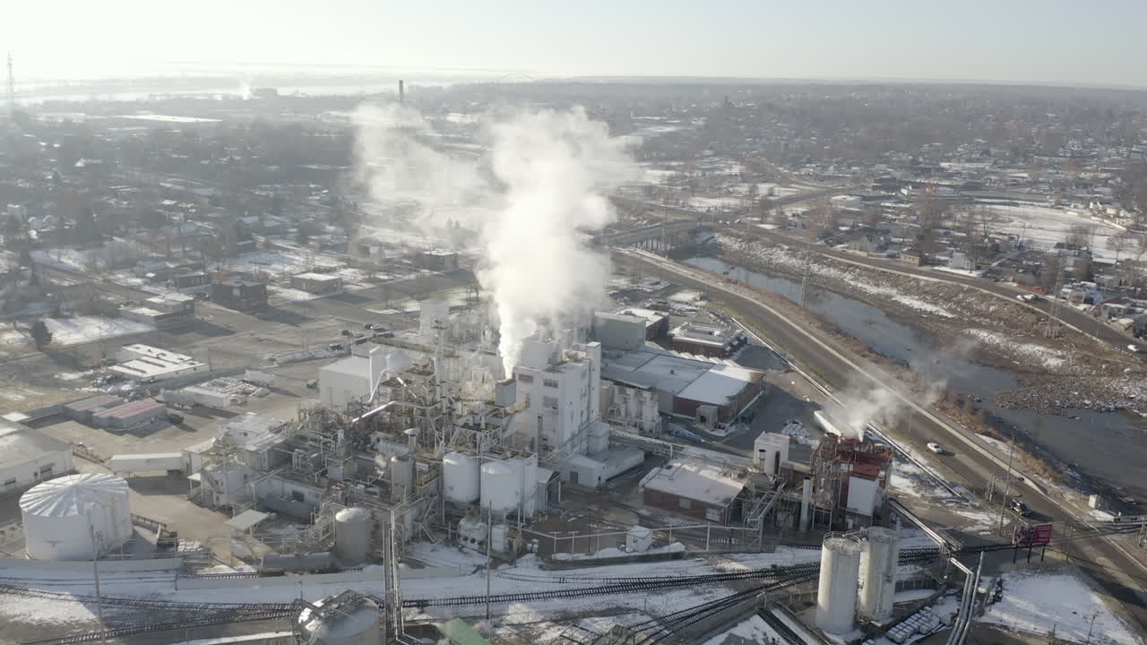 Slow aerial approach over city factory during winter day