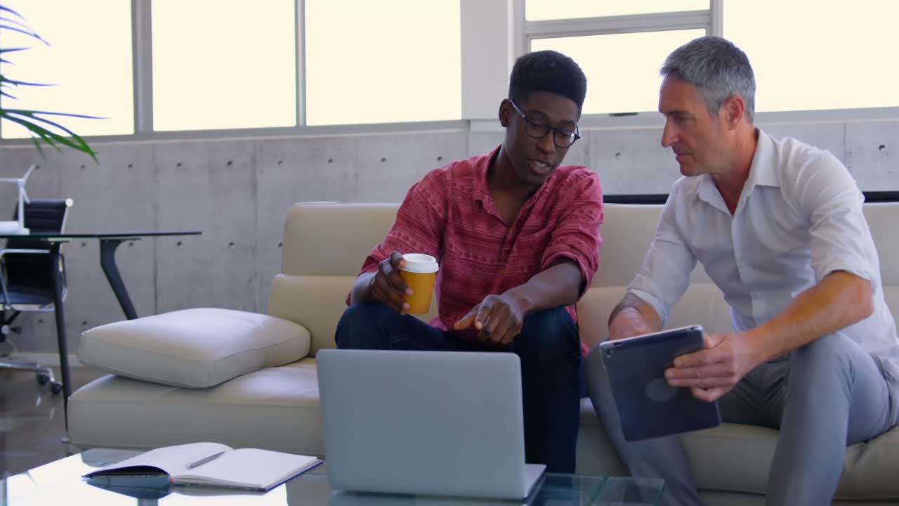 Multi-ethnic male executives discussing over laptop in modern office 4k