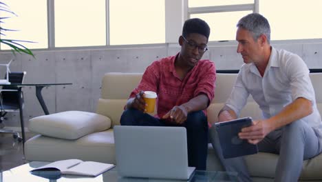 Multi-ethnic-male-executives-discussing-over-laptop-in-modern-office-4k