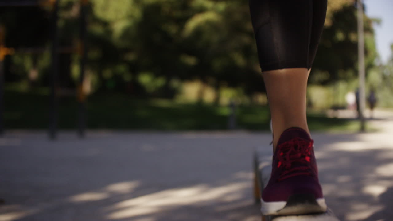 Young woman exercises on a balance beam in a park in Madrid, Spain, close up