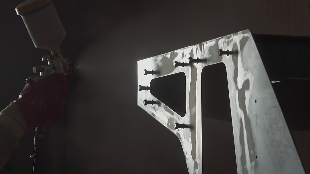 직원이 작업장에서 에어 브러시로 금속 세부 사항을 칠합니다.