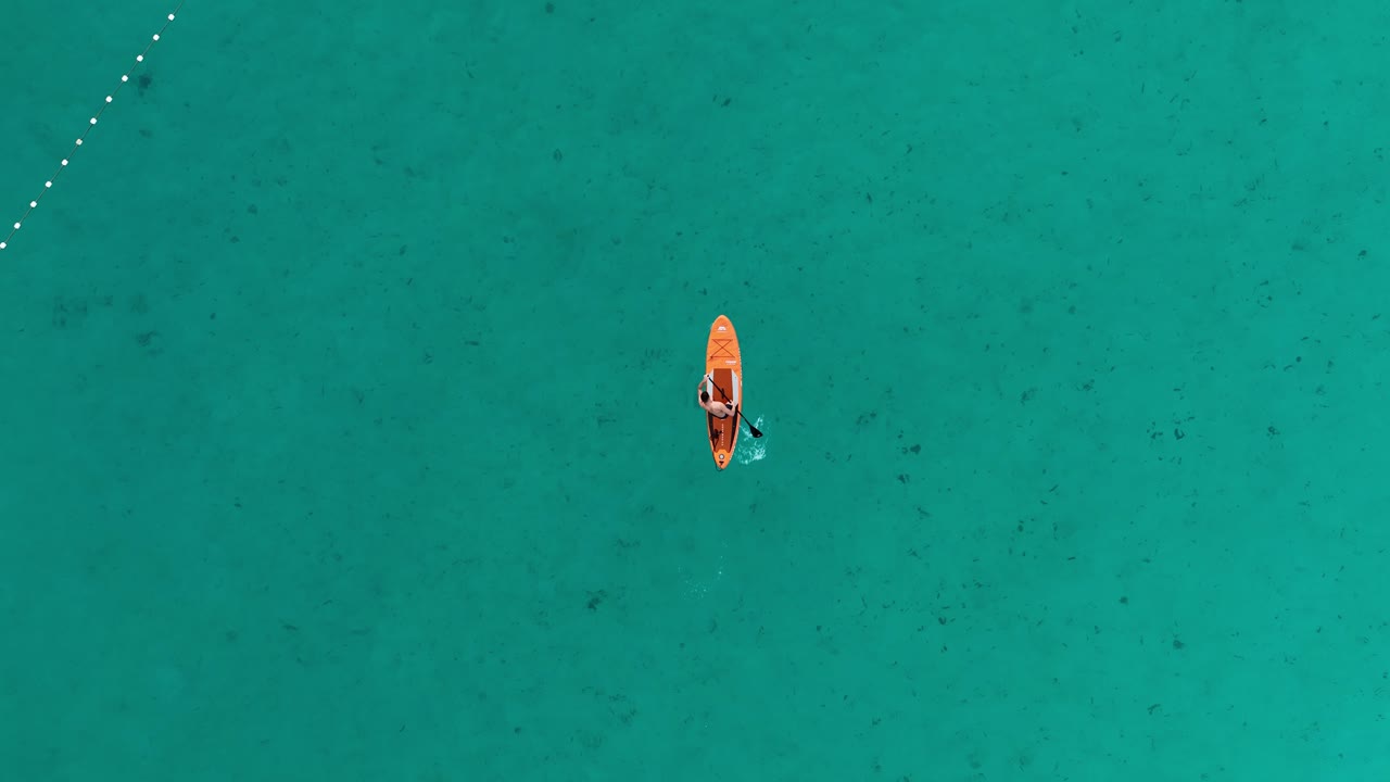 Drone overhead view of a stand-up paddle board in a beautiful turquoise sea.