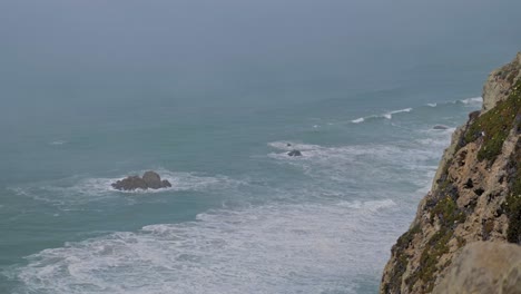 Vista-En-Cámara-Lenta-Desde-El-Acantilado-En-Las-Olas-Y-Las-Montañas,-Cabo-Roca,-Portugal