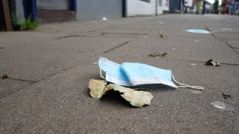 Basura-De-La-Máscara-Facial-Del-Virus-De-La-Corona-En-El-Suelo-En-Una-Calle-Tranquila-De-La-Ciudad