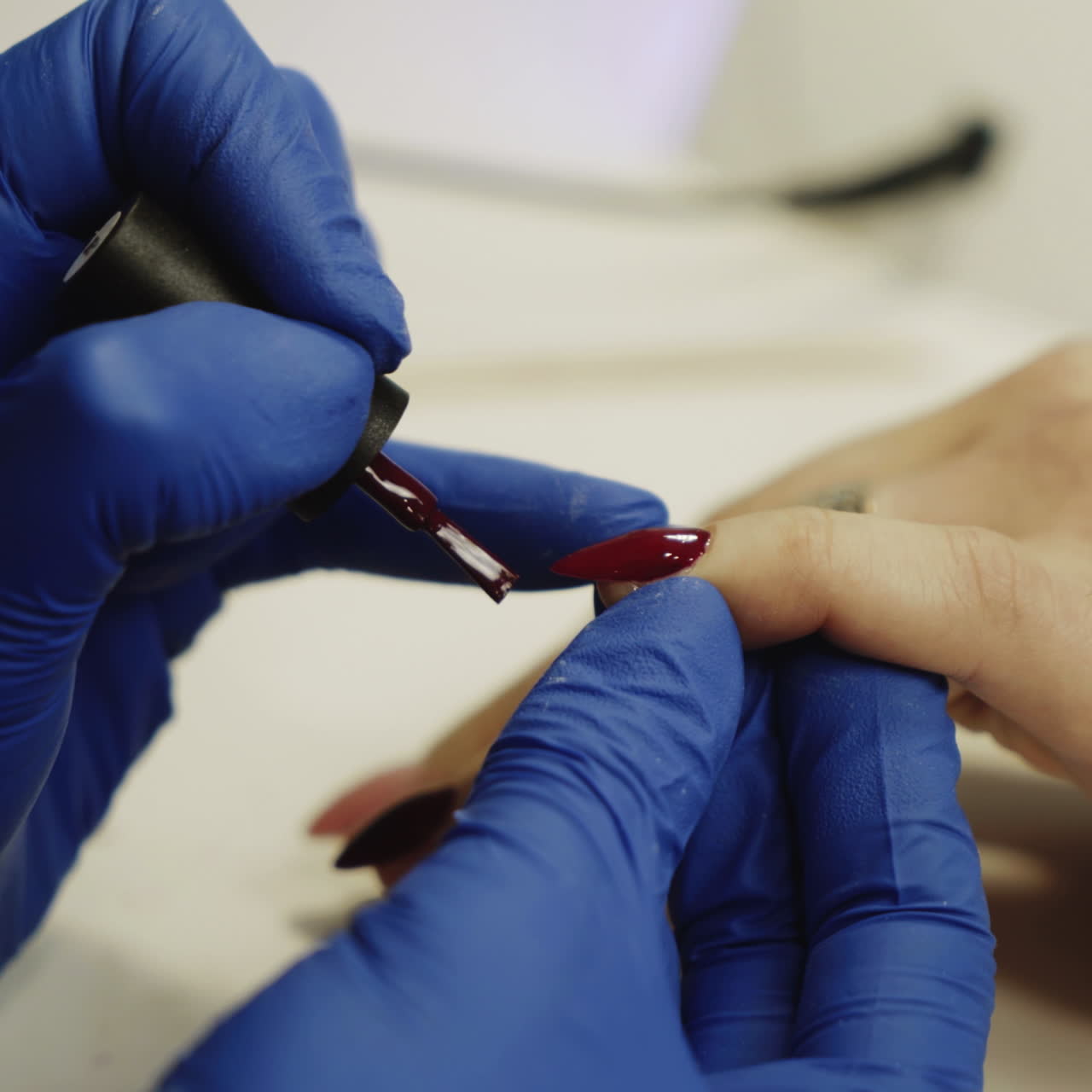 Process of doing manicure in the spa salon. Beautician applying red nail polish on the nails in the beauty salon. Concept of hand care. Square video