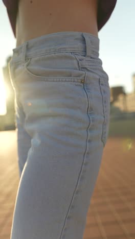 woman in light blue jeans on rooftop at sunset