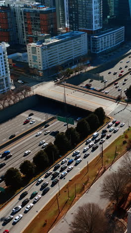 drone flying above the busy highway in atlanta downtown. view on the traffic in metropolis on sunny day. vertical video