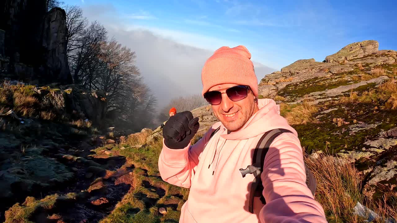 Man hiking and taking selfies on a rugged mountain trail in cold weather