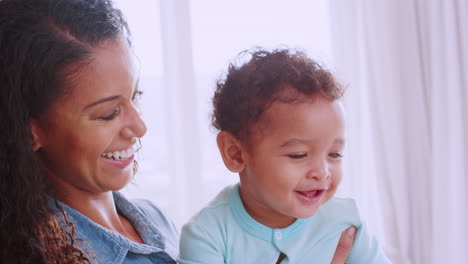 happy young black mum holding her smiling toddler son