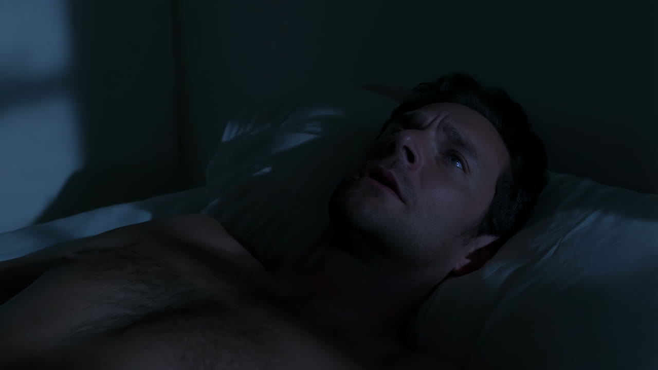 Uomo irrequieto sdraiato sveglio nel letto di notte che soffre di insonnia