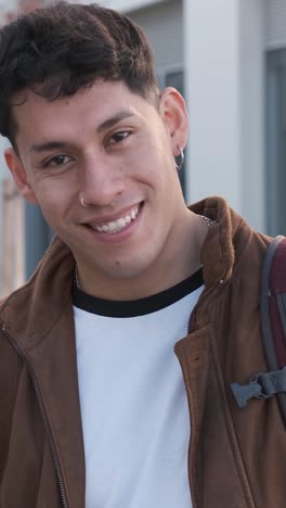 smiling latin young man looking at the camera outside the university