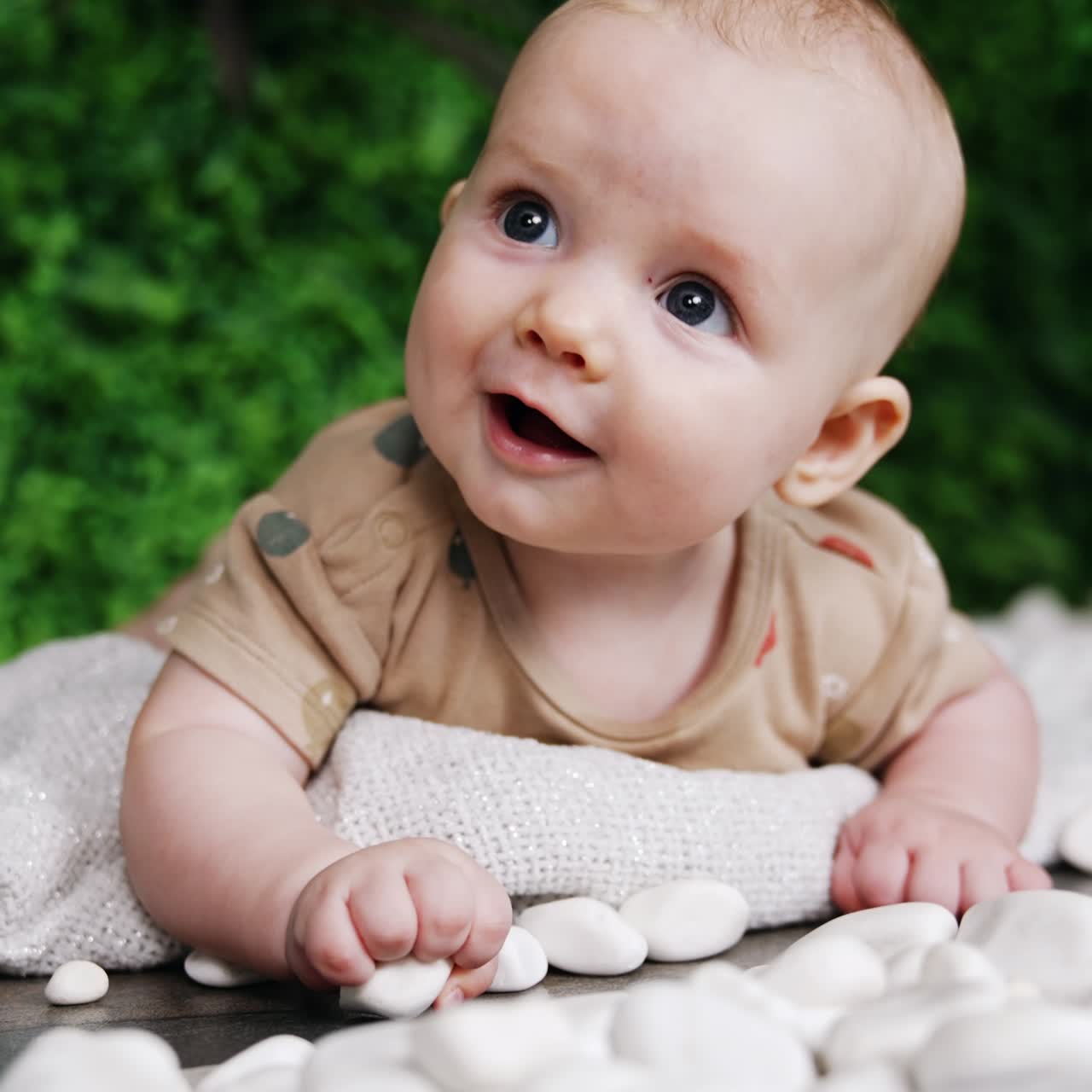 Um lindo bebê deitado de bruços sobre um tecido xadrez. Um bebê caucasiano sorridente olha para cima com um sorriso. Tela vertical