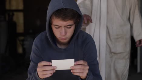 Jesus-wearing-a-white,-tattered-robe-stands-behind-a-young-teenage-boy