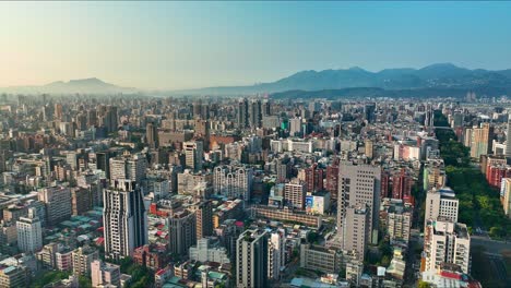 aerial flyover beautiful cityscape of taipei with skyscraper buildings during sunny day with fog between mountains at horizon - downtown with renai road in the morning