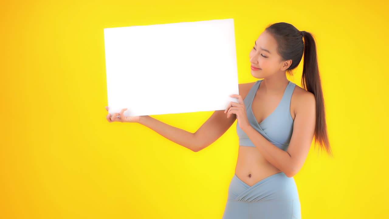 Message template , healthy young attractive woman in workout clothes holds up a blank white sign