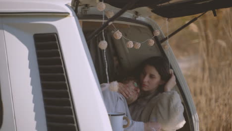 a young couple in love embracing in the back of a caravan by a lake