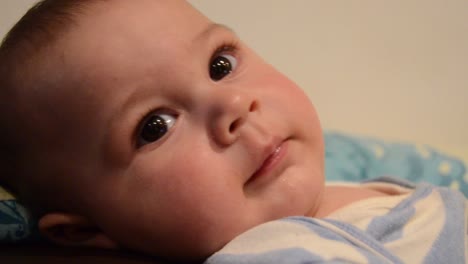 close up overhead shoot of baby boy lookig at the camera and trying to reach it