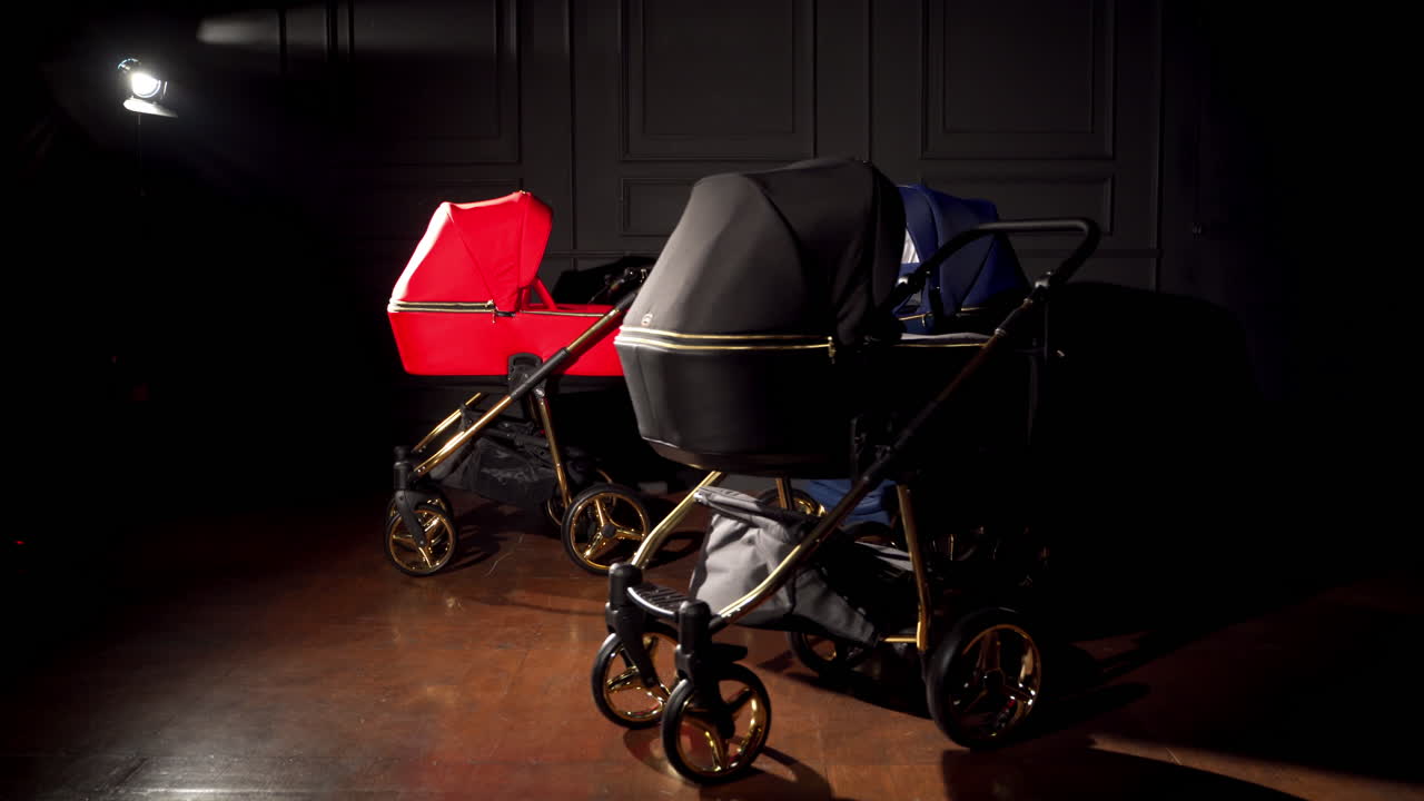 Baby prams are displayed in a light of one lamp. Pushchairs presentation in a dark room.