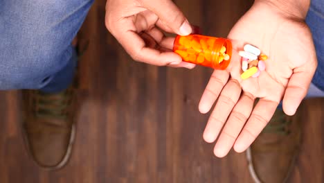 person holding a pill bottle and pills in their hands.