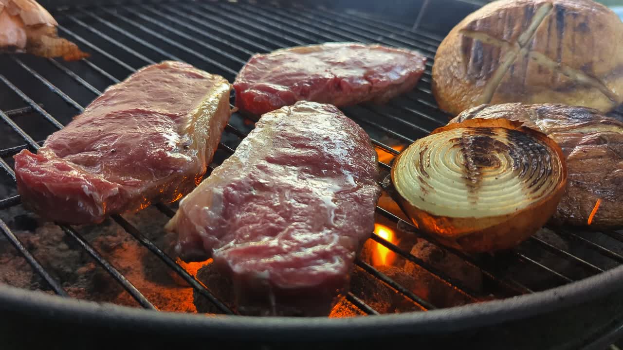 Barbecue beef steaks and mushrooms grilling on the flames over the hot coals.