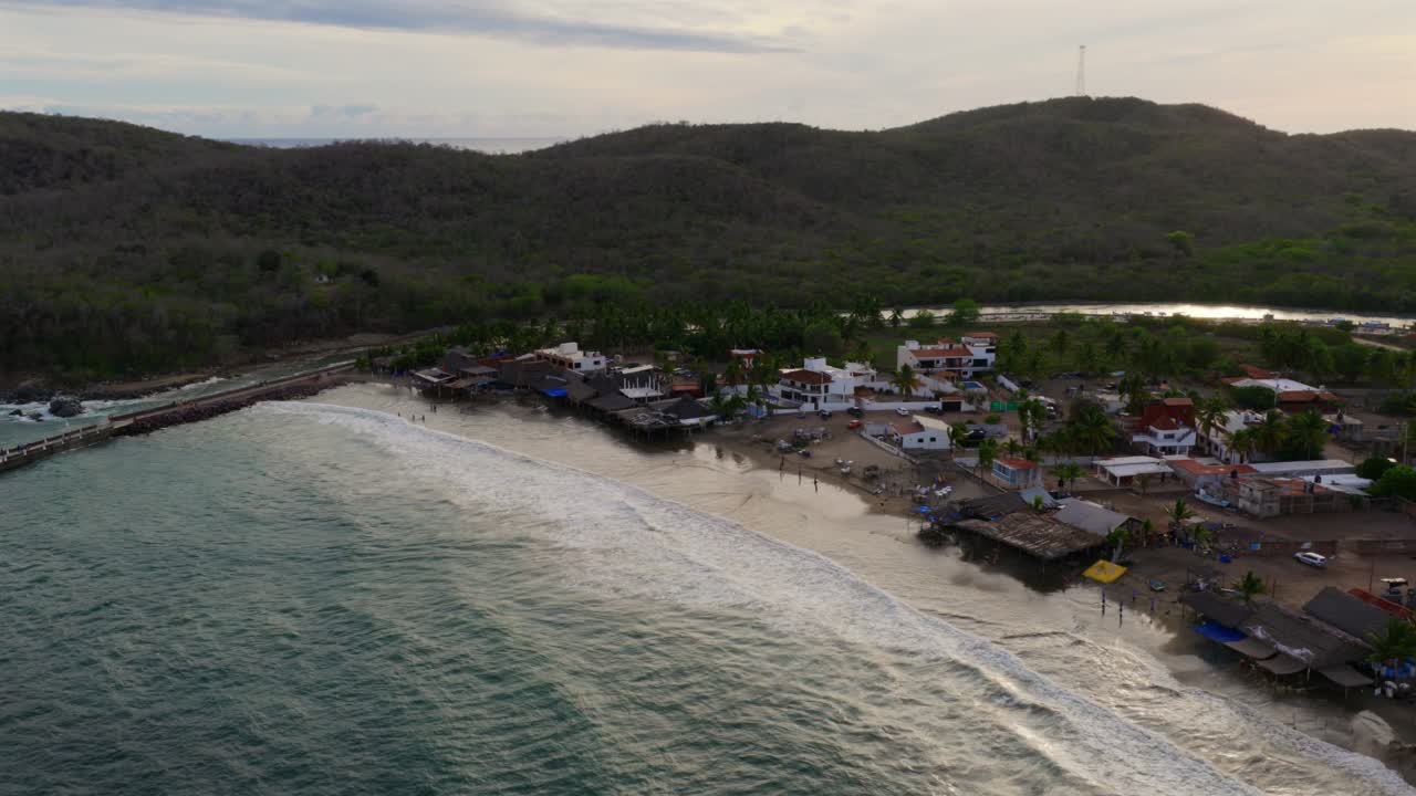 Aerial footage captures Punta Perula's scenic coastline in Jalisco, Mexico. The tranquil dusk lighting highlights both the sea's vastness and the village's charm