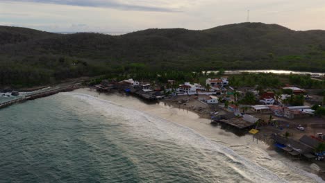 aerial footage captures punta perula's scenic coastline in jalisco, mexico. the tranquil dusk lighting highlights both the sea's vastness and the village's charm