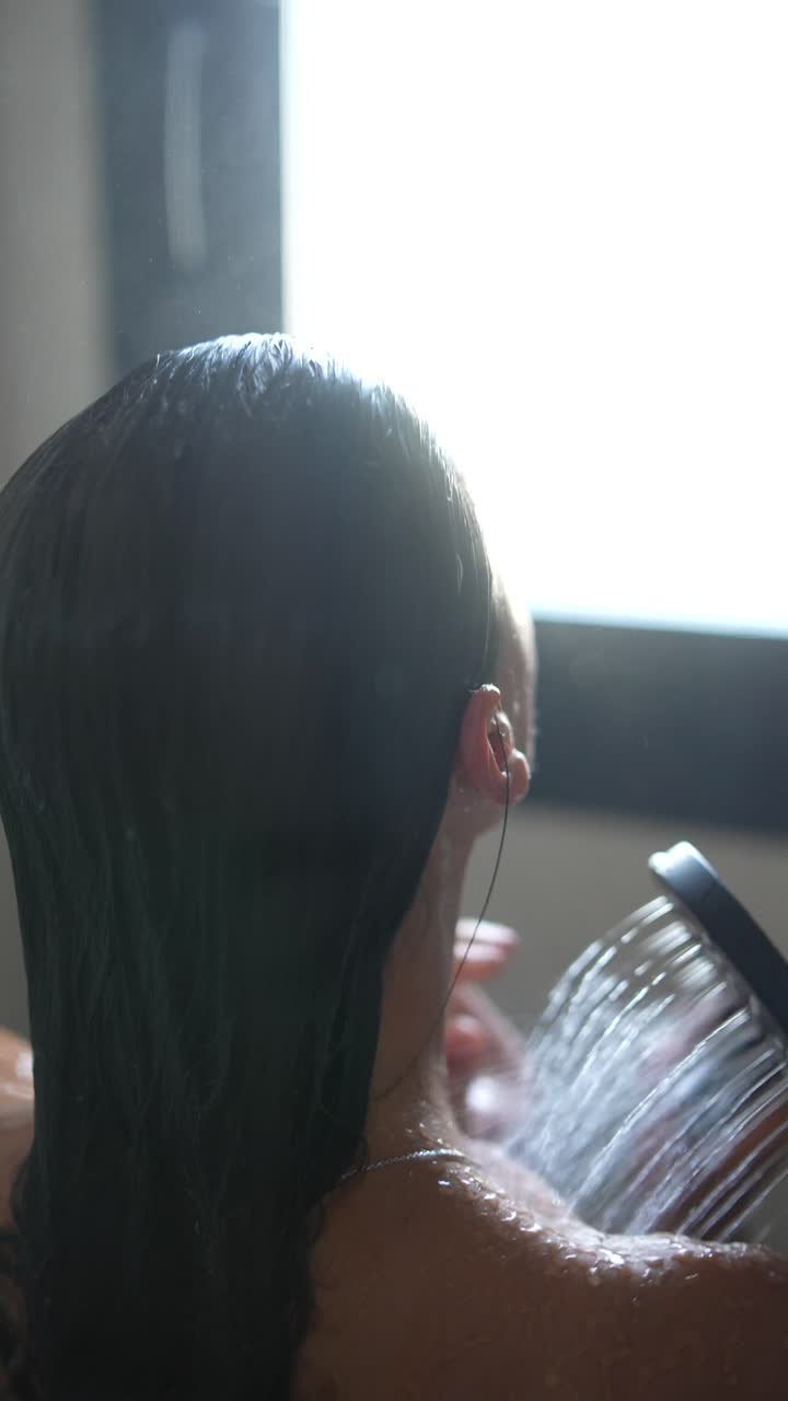 Donna che si lava i capelli sotto la doccia