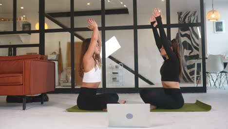 dos mujeres practicando yoga en casa