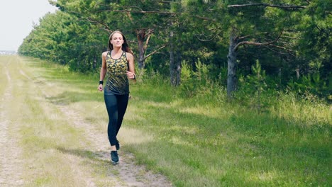 CU-Portrait-Young-pretty-girl-goes-in-for-sports-in-the-morning-runs-along-a-pine-forest