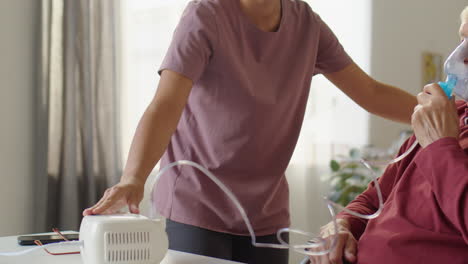 caregiver assisting elderly man with nebulizing at home