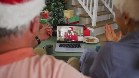 Happy-caucasian-senior-couple-couple-on-video-call-with-santa-claus-at-christmas-time