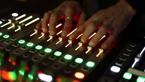 primo piano del pannello del mixer tv con le mani che spostano i pulsanti che controllano il livello di audio e video