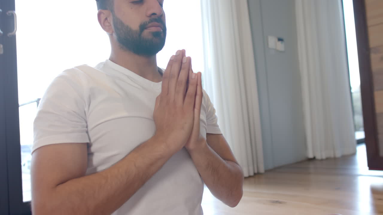 Uomo birazziale che fa yoga e medita a casa, al rallentatore.