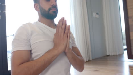 biracial man doing yoga and meditating at home, slow motion