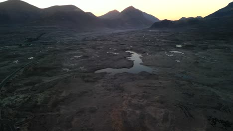 Pan-up-revealing-Red-Cuillin-mountains-at-dawn-with-Loch-Caol-at-Sligachan-on-the-Isle-of-Skye-Scotland