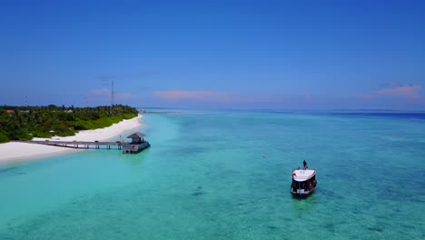 man standing on top of tour boat as it heads to harbor on beautiful maldives island