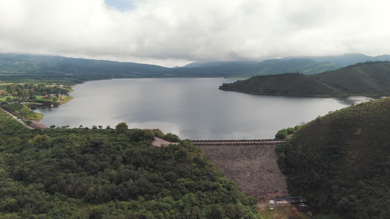 Aerial view of a large dam and reservoir surrounded by lush green mountains