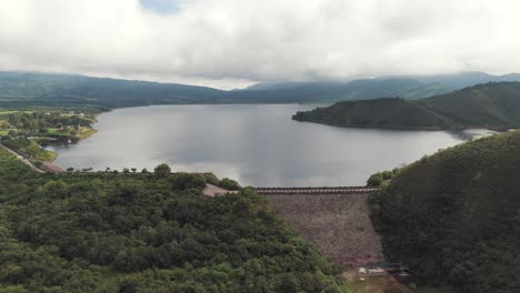 aerial view of a large dam and reservoir surrounded by lush green mountains