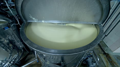 big cistern with automatic mixing system inside. beating the butter in automatic mixer tank. butter production at milk factory close up.